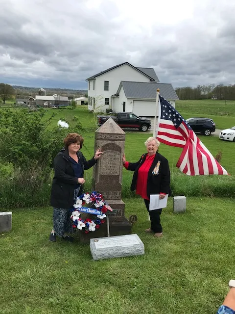 Two chapter members beside the headstone and wreath
