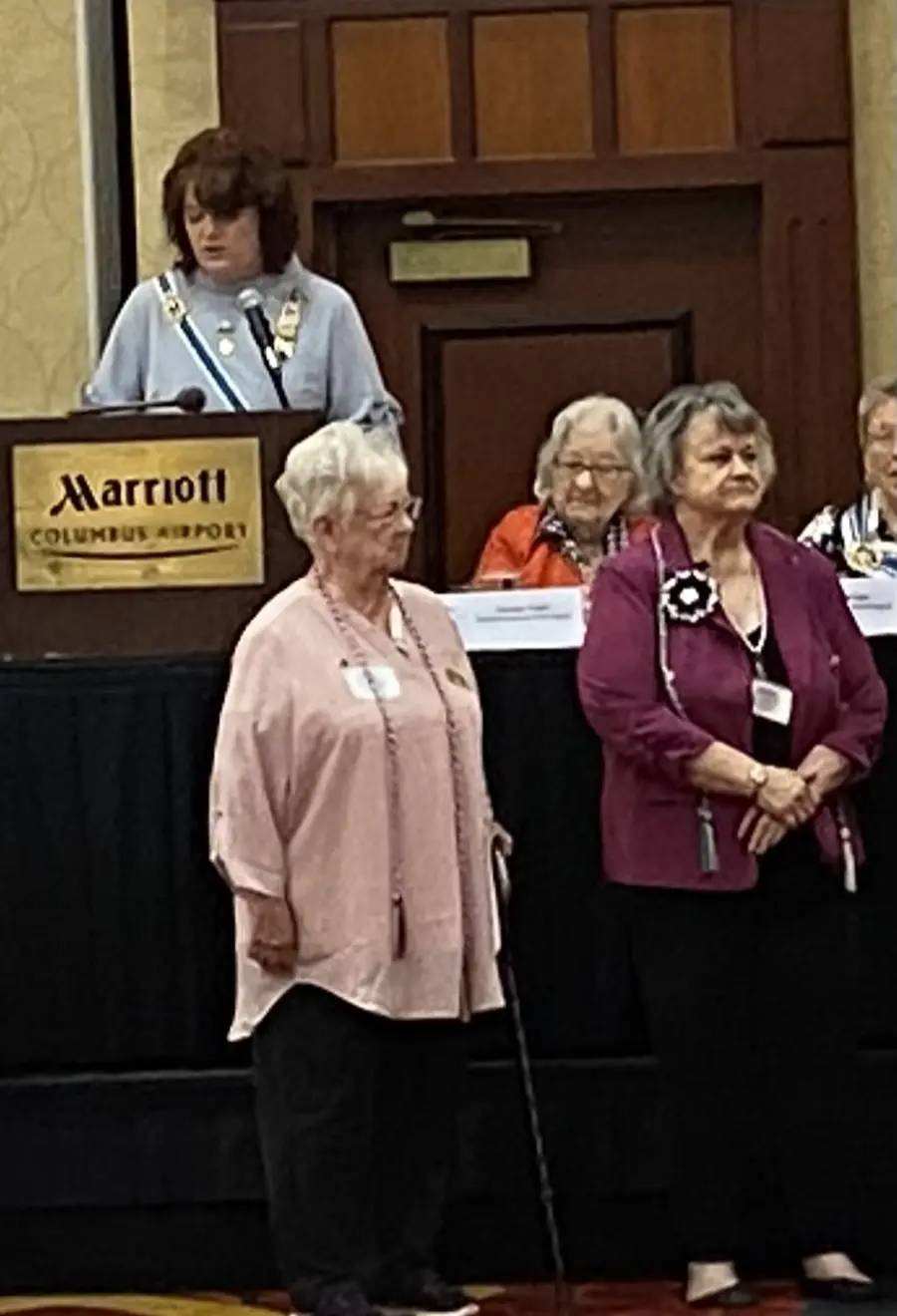 Two chapter members standing before the head table at the State Committee Showcase