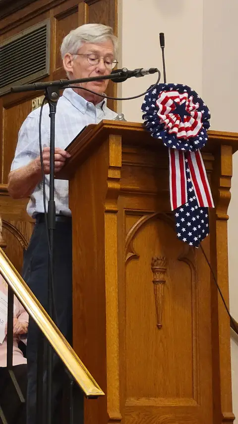A community reader at the podium reading from the Constitution