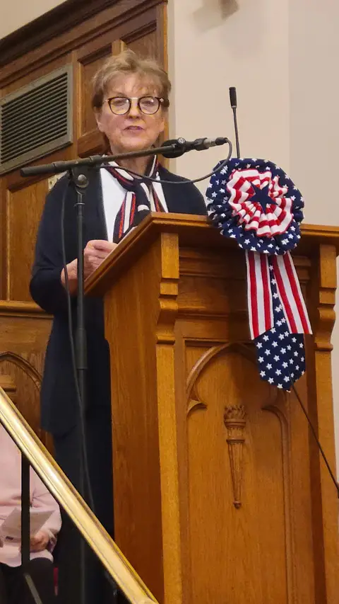 A community reader at the podium reading from the Constitution