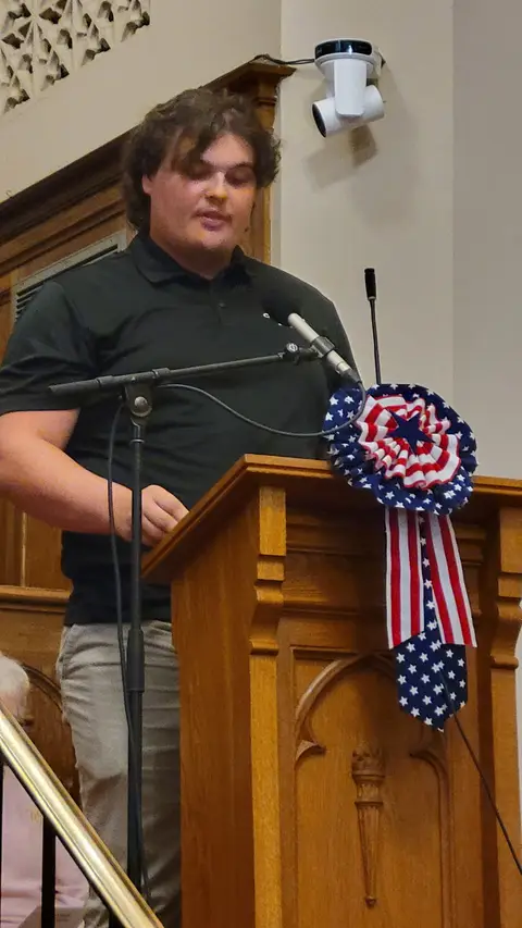 A community reader at the podium reading from the Constitution