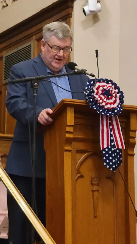 A community reader at the podium reading from the Constitution
