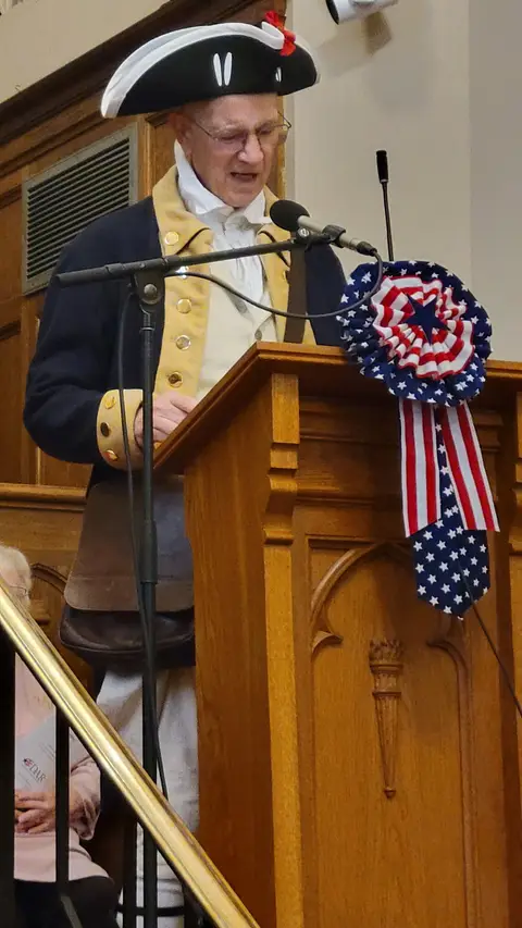 A community reader at the podium reading from the Constitution
