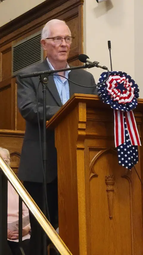 A community reader at the podium reading from the Constitution