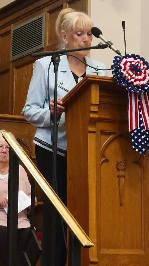 A community reader at the podium reading from the Constitution